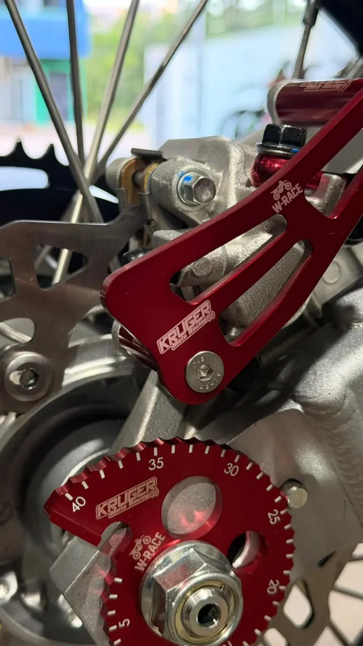 Detalhe de suporte usinado vermelho com logo Kruger